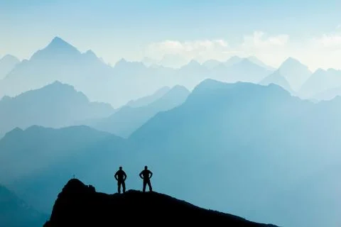 Two Men reaching summit after climbing and hiking enjoying freedom and looking Stock Photos