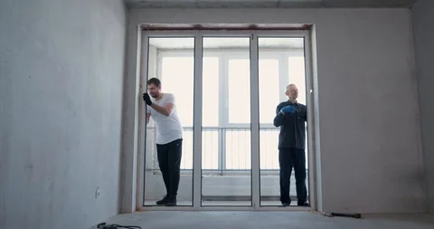 Two men at real estate object under construction dismantle plastic window, cut Stock Footage 129838797