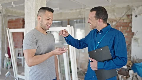 Two men real state agent and client holding keys of new home at constructio.. 스톡 동영상 241142607