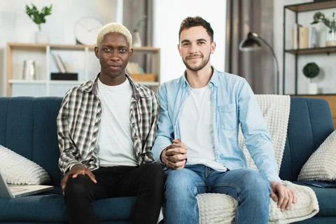 Two men in relations holding hands while sitting on sofa 스톡 사진