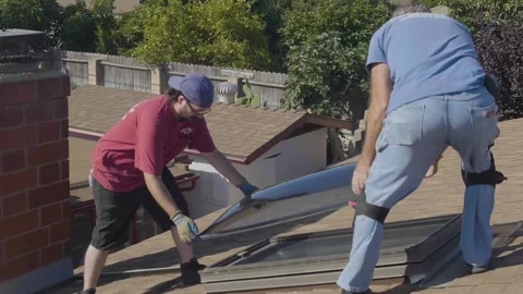 Two Men Replacing a Large Skylight Window on a Rooftop Stock Footage 212417545