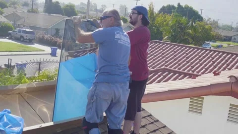 Two Men Replacing a Skylight Window on a Roof Peeling the Protective Film Stock Footage 212417477