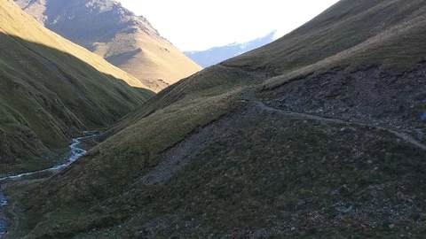 Two men ride along the cliff with river. Stock Footage 83764320