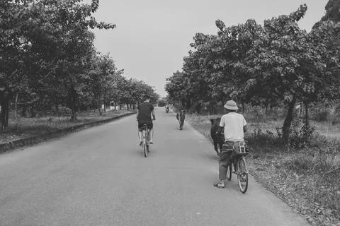 Two men riding bicycles down a quiet rural road in Vietnam Stock Photos