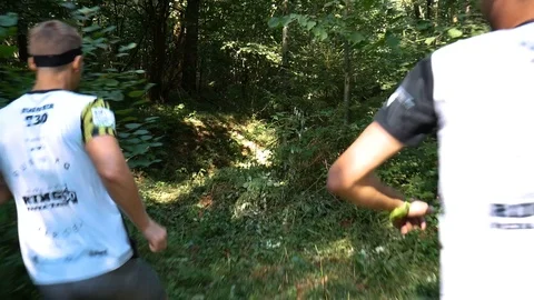 Two men runners run and jump through the trees Stock Footage 93846348