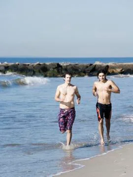 Two men running on the beach Stock Photos