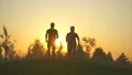 The two men running on the grass on a beautiful sunset background. slow motion 4k or 4k+ Resolution