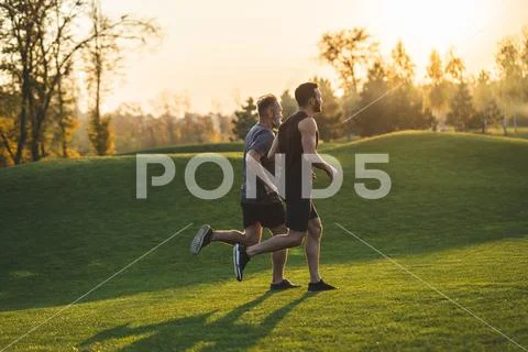 The two men running on the grass in the park Stock Photos
