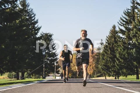 The two men running on the road in the park Stock Photos