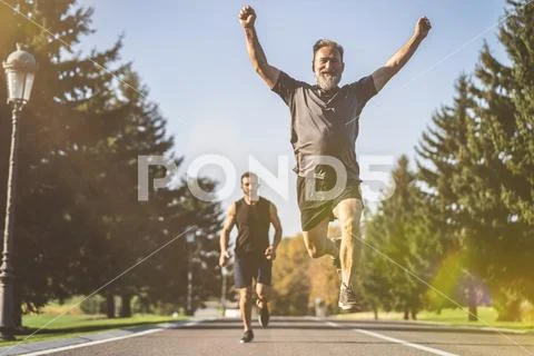 The two men running on the road in the park on the sunny background Stock Photos