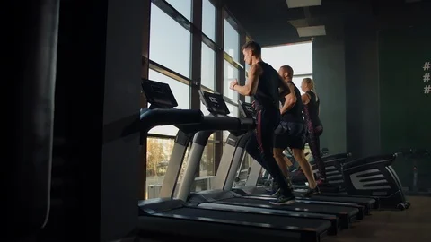 Two men running on a treadmill in the background of a large window in the Video stock 118521472
