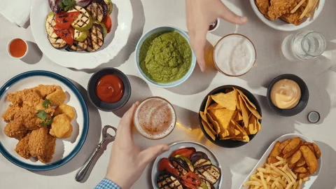 Two men at the same table raise their beer glasses and clink them together Stock Footage 144536057