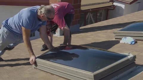 Two Men Screwing in a New Skylight Window on a Rooftop Stock Footage 212418140