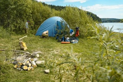 Two men set up a campsite, set up a tent on the river bank Stock Photos