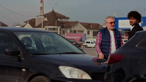 Two men shake hands after resolving a small conflict in the parking lot. Two Stock Footage 242610315