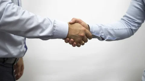 Two men shake hands against a white wall Stock Footage 124149976