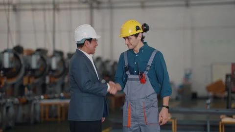 Two men shake hands in a factory setting Stock Footage 340269200