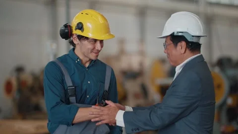 Two men shake hands in a factory setting Stock Footage 340269201