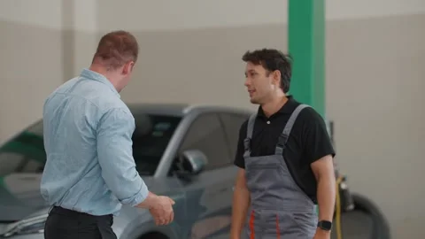Two men shake hands in a garage Stock Footage 339050365