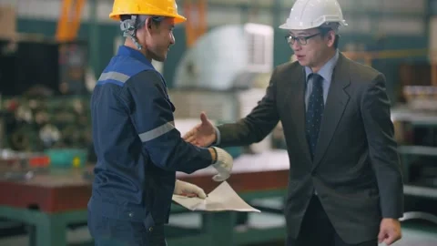 Two men shake hands in an industrial setting Stock Footage 345135690