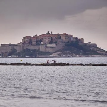 Two men shake hands at the see in front of Calvi Stock Photos