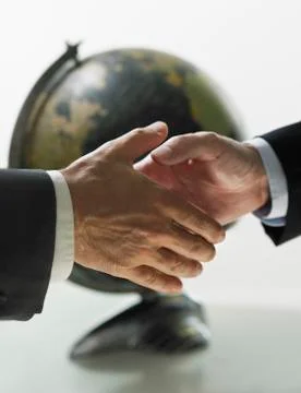 Two men shaking hands with globe in background Foto stock
