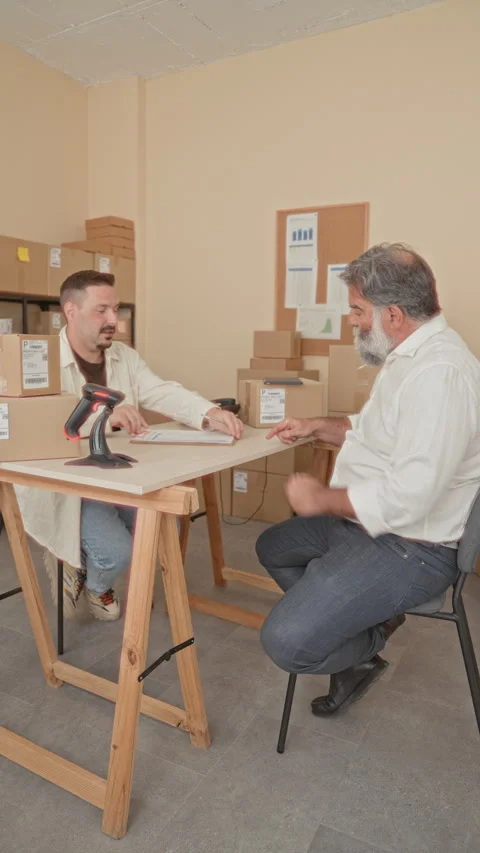 Two men signing parcel paperwork with hands and barcode scanner in a small .. Video stock 339215806