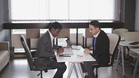 Two men sit in armchairs at the office and talking Stock Footage 81057172