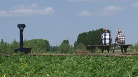 Two men sit on a bench in river landscape - wide shot Stock Footage 64765133