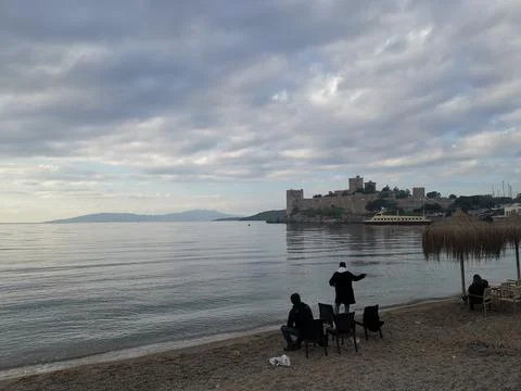 Two men sit on chairs on the seashore and look at The Castle of St Peter Stock Photos