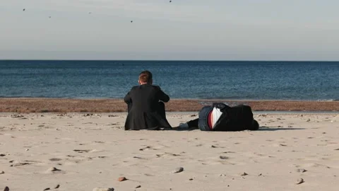 Two men sitting on the beach talking. They drink alcohol. Stock Footage 155489692