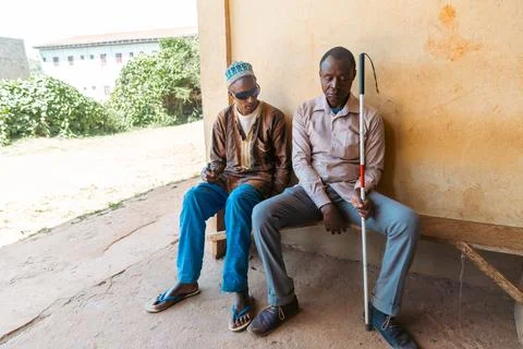 Two men sitting on a bench, one of them holding a cane Stock Photos