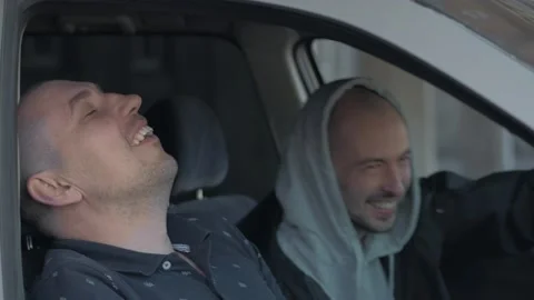 Two men sitting in a car, talking and laughing Stock Footage 154203235