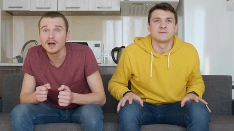 Two men sitting on the couch watch a football match on TV Stock Footage 107650072