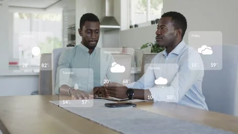 Two men sitting at dining table, weather widgets appearing over table, sharing Stock Footage 333552476