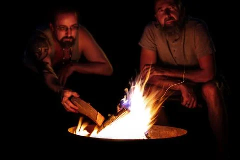Two Men sitting on a fire, campfire on a fireplace at night, outdoor lifestyl 写真素材
