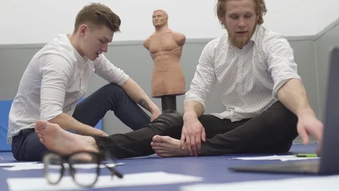 Two men sitting on the floor in the gym, papers and glasses in front and dummy Video stock 107046524