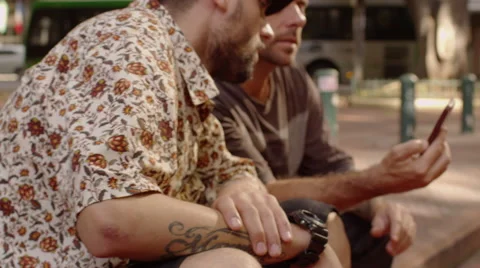Two men sitting on the footpath and looking at the phone Video stock 61273754