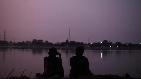 Two men sitting by the lake 動画素材 242029206