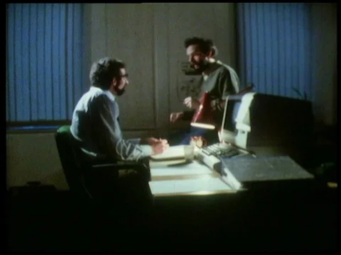 Two men sitting in office, talking about program helping with daily tasks, 1985 Stock Footage 136675933