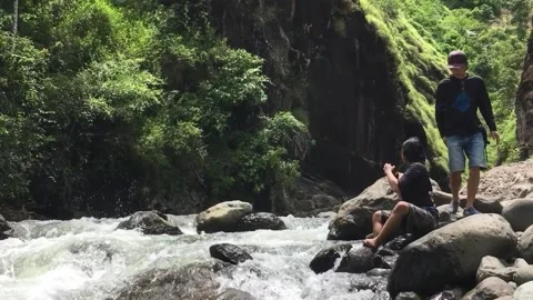 Two Men Sitting by a River, Leuwi Tonjong, Garut, West Java, Indonesia. Видео 343415644