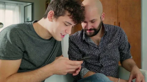 Two men sitting on sofa, looking at smart phone, Italy Video stock 147082267