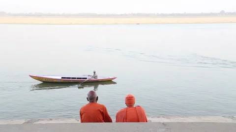Two men sitting on stairs and watching boat sailing on Ganges river. Stock Footage 50400372