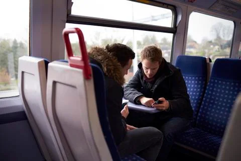 Two Men Sitting In Train Carriage Looking At Text Message Stock Photos