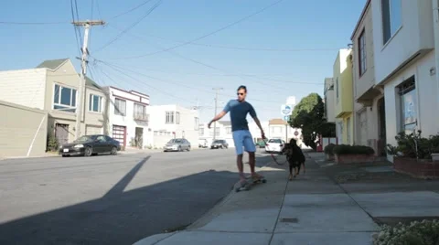 Two Men Skating with Pet Dogs Stock Footage 22198698