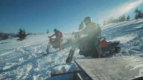 Two men in ski suits sitting on snowmobiles, wear helmets. Guys started riding Stock Footage 194403202