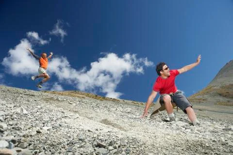 Two Men Sliding Down Scree Field Stock Photos