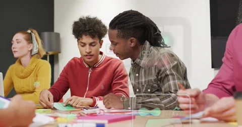 Two men sorting paper and folding green piece, leaning in, guiding assembly in Stock Footage 331272935