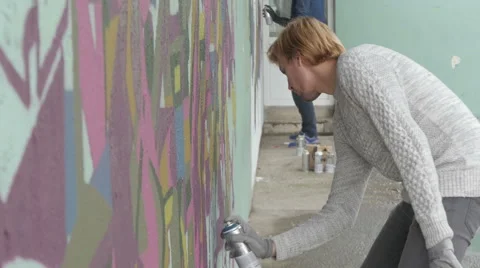 Two men with sprays drawing graffiti deson wall, shallow depth of field. Stock Footage 57139051