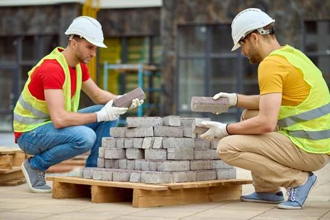 Two men stacking bricks at construction site Stockfoto's